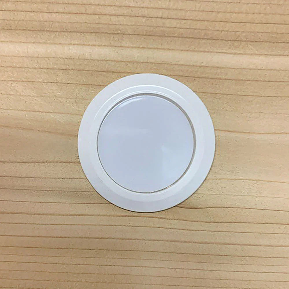 Bouchon blanc rond installé sur une planche de bois clair, accessoire pour ébénisterie.