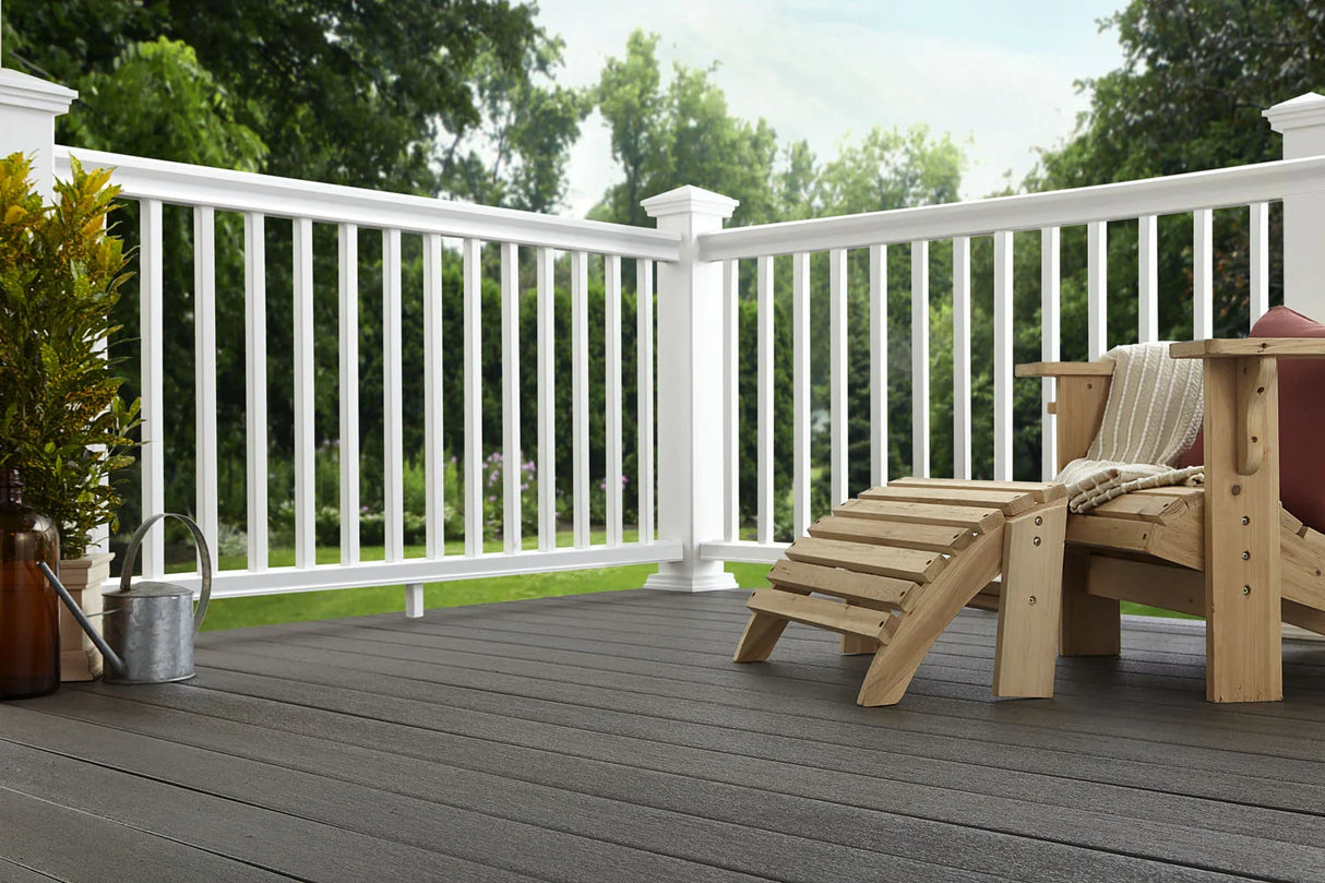 Terrasse avec planches composites gris graphite, fauteuil en bois et rambarde blanche extérieure