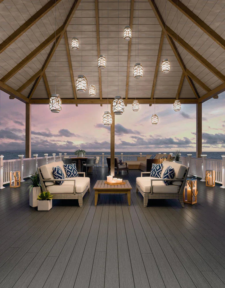 Terrasse en composite gris graphite avec mobilier d’extérieur sous un pavillon au coucher du soleil