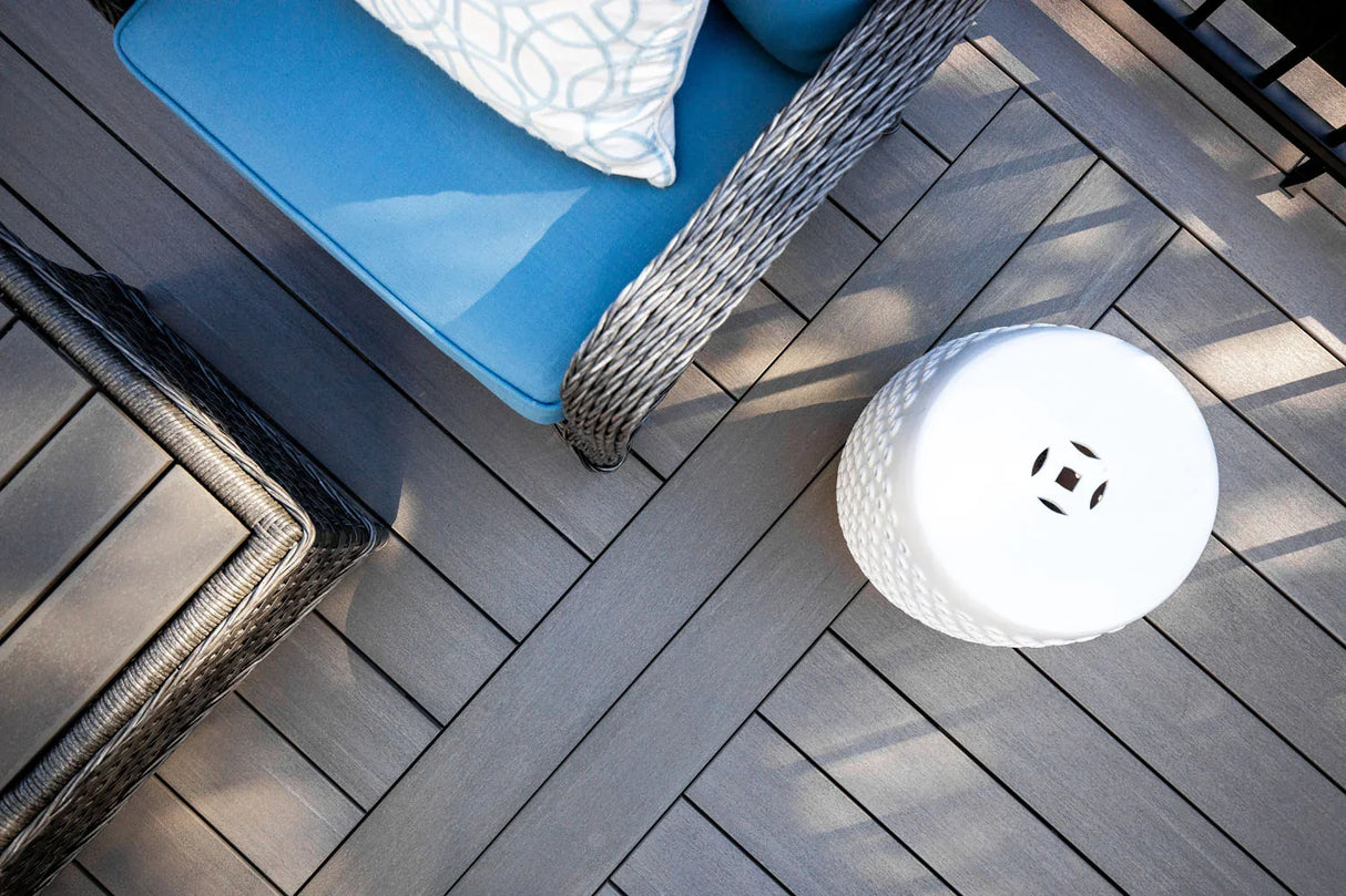 Terrasse en composite gris avec fauteuil bleu et tabouret blanc, agencement moderne