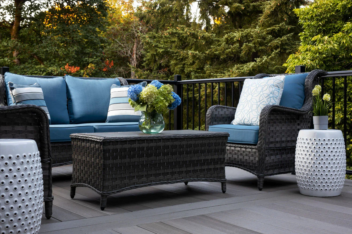 Terrasse en bois composite avec mobilier d'extérieur, coussins bleus et jardinières, en forêt.