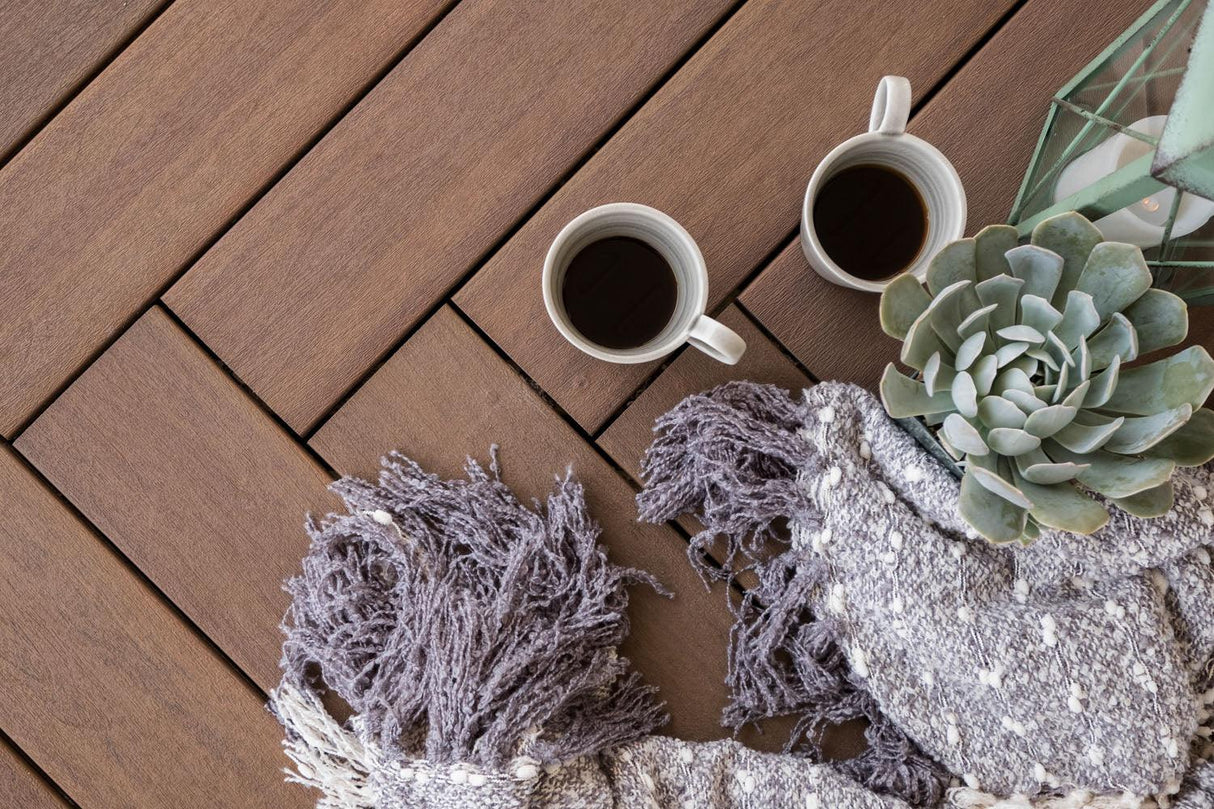 Planches de terrasse composite brun chaud avec deux tasses, plaid et plante succulente