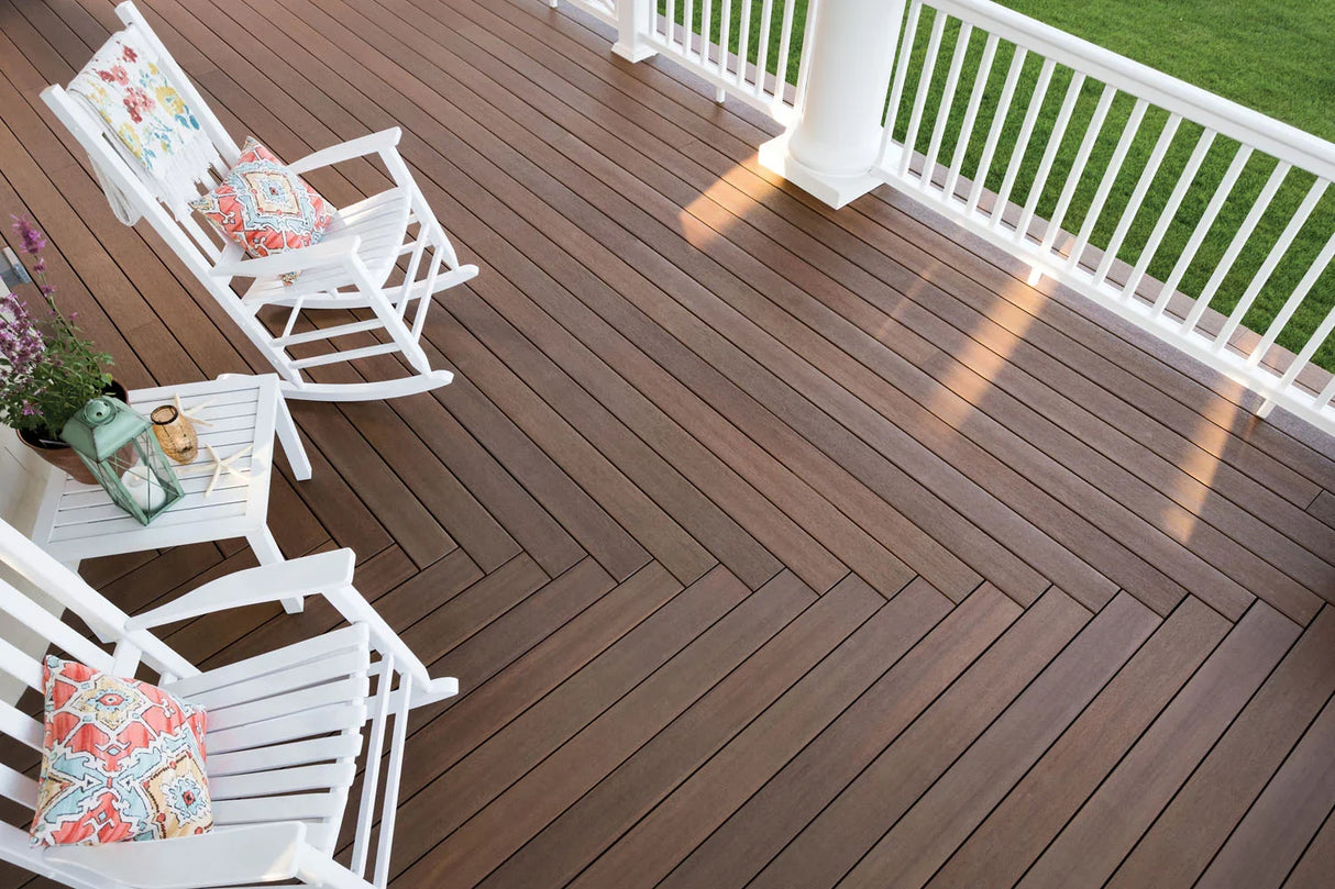 Terrasse en bois composite brun, fauteuils blancs, rambarde blanche, déco extérieure élégante.