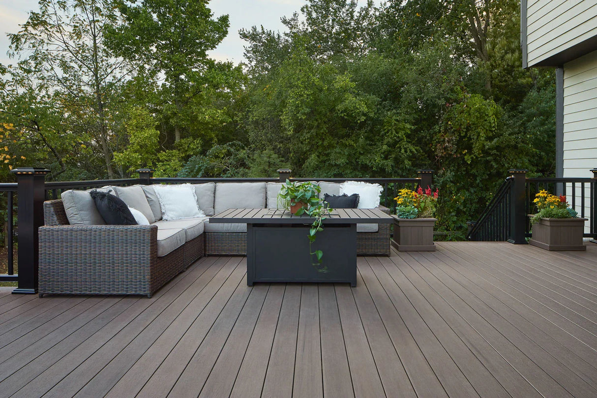 Terrasse en bois composite avec canapé d'extérieur, table basse et jardinières fleuries