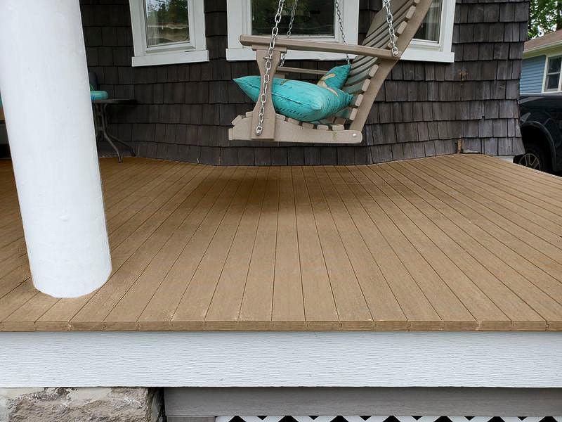 Plancher de terrasse en bois composite effet teck vieilli avec balançoire suspendue.