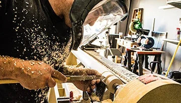Ébéniste travaillant le bois sur un tour, copeaux volants, atelier de menuiserie à Montréal