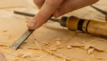 Main sculptant du bois avec un ciseau à bois, copeaux, ébénisterie artisanale Montréal