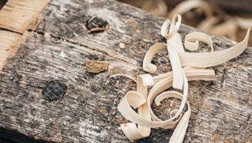 Copeaux de bois clair sur planche brute, ébénisterie artisanale à Montréal