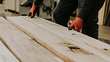 Homme manipulant des planches de bois brut en atelier d'ébénisterie, bois massif Montréal