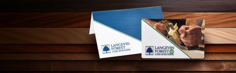 Carte cadeau ébénisterie exposée sur des planches de bois, main utilisant un rabot.
