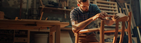 Ébéniste travaillant sur une chaise en bois dans un atelier de fabrication de meubles