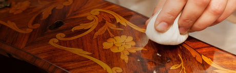 Finition à la main d’un meuble en bois sculpté avec motifs floraux, restauration ébénisterie.