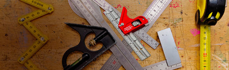 Outils de mesure d'ébénisterie sur établi en bois, règles métalliques et mètres ruban