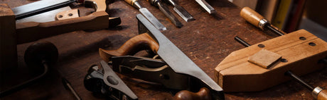 Outils d'ébénisterie en bois et métal sur un établi, scie, rabot, ciseaux à bois.
