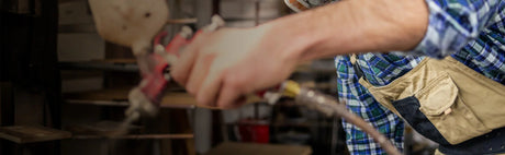 Artisan appliquant une finition au pistolet sur bois dans un atelier d'ébénisterie