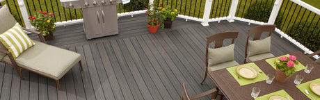 Terrasse en composite gris avec mobilier de jardin, barbecue et plantes en pots