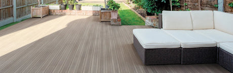 Terrasse en composite beige avec canapé extérieur et jardinières, idéale pour aménagement de jardin