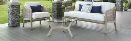 Terrasse en bois composite gris, mobilier de jardin moderne, coussins bleus et espace vert