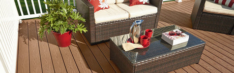 Terrasse en composite marron avec salon de jardin, table basse, plante verte et tasse rouge