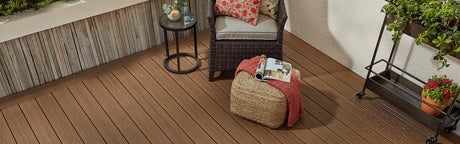 Terrasse en composite brun avec fauteuil, table, pouf et plantes décoratives