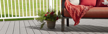 Plancher de terrasse composite gris, fauteuil orange, plante en pot, rambarde blanche extérieure