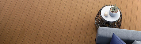 Terrasse en composite imitation bois avec table d’appoint, plante et canapé gris