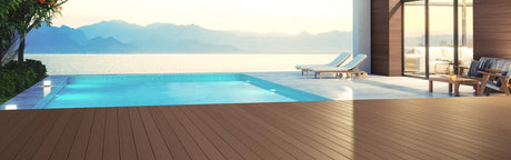 Terrasse en composite marron près d'une piscine, transats et vue sur le lac au coucher de soleil