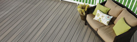 Terrasse en composite gris avec canapé d’extérieur et coussins verts, idéale pour jardin