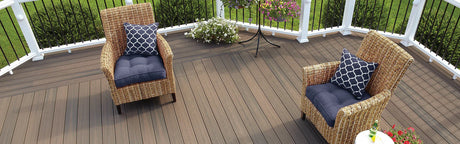Terrasse en composite avec chaises en rotin, coussins bleus et plantes fleuries extérieures