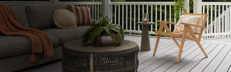 Terrasse extérieure avec planches en PVC gris, fauteuil en bois, table basse et plantes décoratives