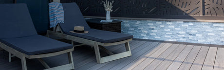 Terrasse en composite gris avec deux chaises longues, table et décor mural moderne extérieur