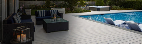 Terrasse en composite blanc autour d'une piscine, salon de jardin et chaises longues élégantes