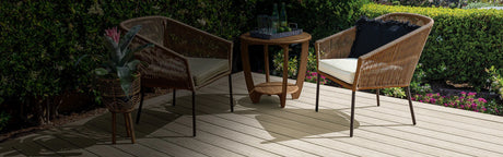 Terrasse en composite avec salon de jardin tressé, table, plantes et haies vertes