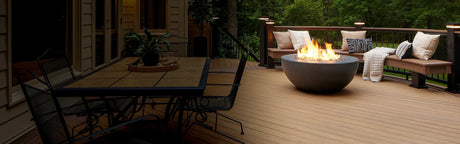 Terrasse en composite avec foyer extérieur, table à manger et bancs, ambiance bois naturel