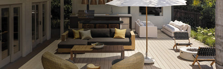 Terrasse en bois composite avec salon extérieur, parasol, foyer et cuisine d'été moderne.