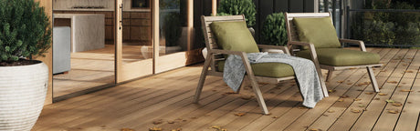 Terrasse en composite avec fauteuils verts, plantes en pot et sol beige, ambiance extérieure moderne