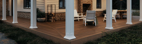 Terrasse en composite brun avec colonnes blanches, meubles de jardin et bûches décoratives
