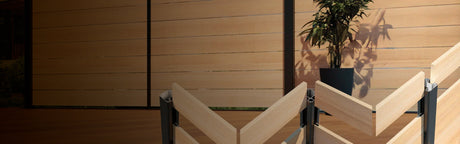 Clôture de terrasse en bois moderne avec panneaux horizontaux et structure noire, plante en pot en arrière-plan
