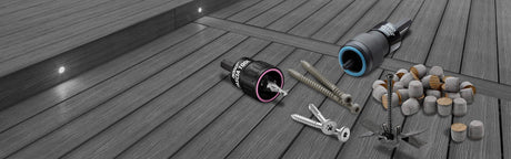Outils d'installation terrasse bois, vis, bouchons et éclairage encastré sur lames gris.