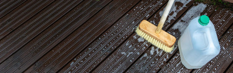 Nettoyage d’une terrasse en bois avec une brosse et détergent, surface humide et mousse