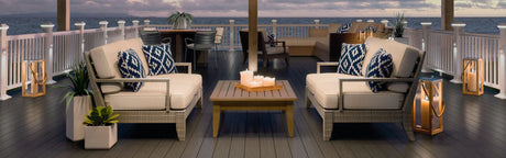 Terrasse en bois avec mobilier de jardin, coussins décoratifs et vue sur l’eau au coucher du soleil