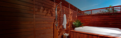 Terrasse extérieure en bois avec douche, spa et palmiers sous ciel bleu