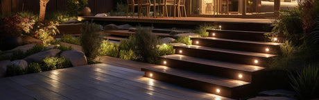 Terrasse en bois éclairée la nuit avec escalier, plantes et mobilier extérieur