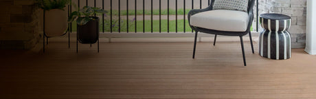 Terrasse en bois composite avec fauteuil extérieur, table d’appoint rayée et jardinière