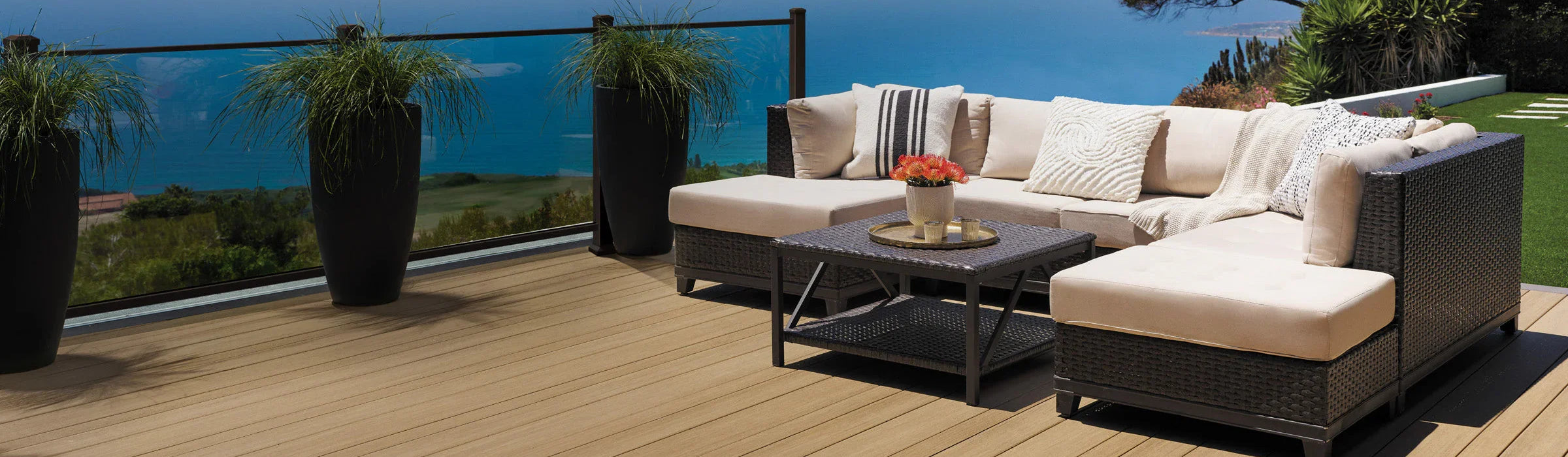 Terrasse en PVC aspect teck vieilli avec salon extérieur, vue sur la mer, plantes vertes en pots