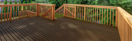 Terrasse en bois avec balustrades, planches horizontales et escalier extérieur, entourée d’arbres