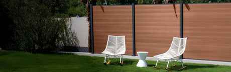 Clôture en PVC imitation bois avec fauteuils de jardin blancs sur pelouse verte