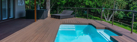 Terrasse en bois composite avec piscine, vue sur jardin, mobilier extérieur moderne