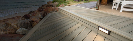 Terrasse en bois composite clair avec éclairage intégré, proche de la plage et des rochers