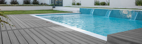 Terrasse en lames composite grises autour d'une piscine moderne avec cascades, jardin paysager
